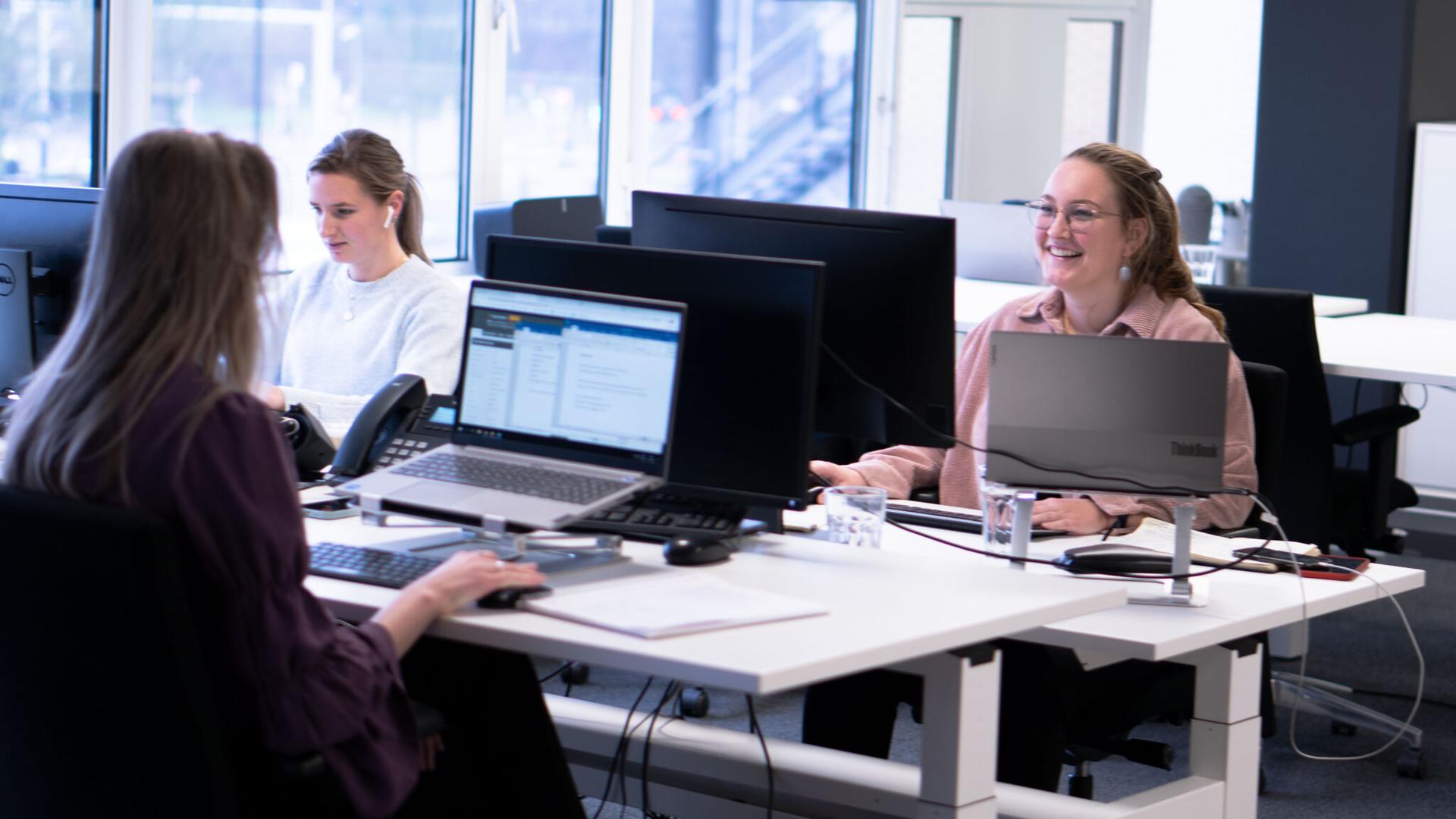 Drie talentcoaches geconcentreerd aan het werk achter hun computers bezig met het ontwikkelen en ondersteunen van talenten in een kantooromgeving