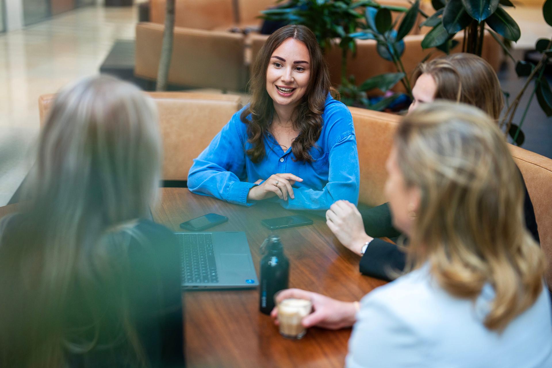 Een jonge vrouw, klaar met haar studie staat buiten met een stapel boeken op haar arm en kijkt optimistisch de camera in