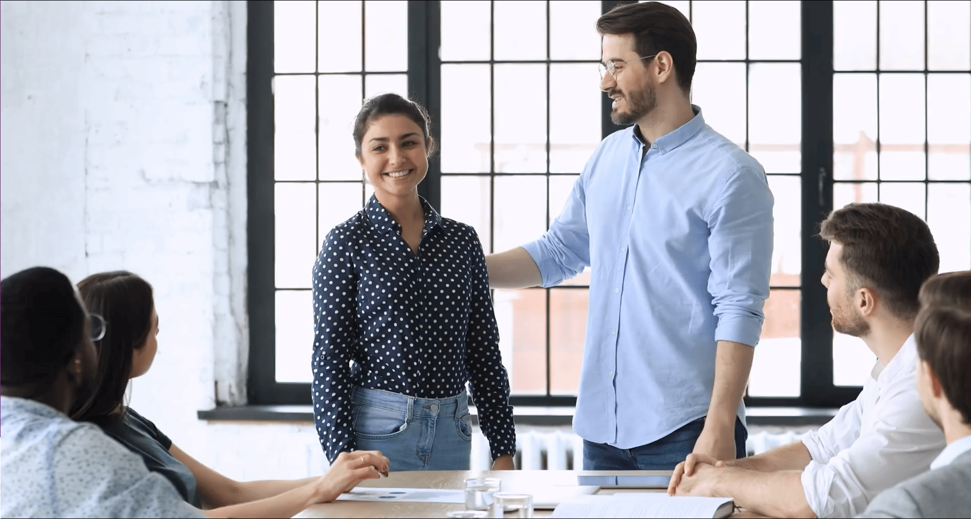 Leidinggevende introduceert een nieuwe collega aan team in devergaderruimte