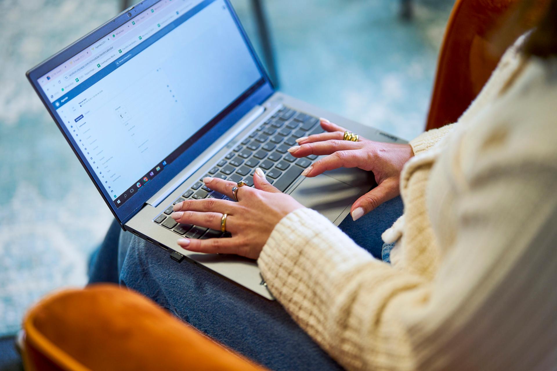 Close-up van een jonge vrouw die op een laptop aan het typen is over het ziekteverzuim