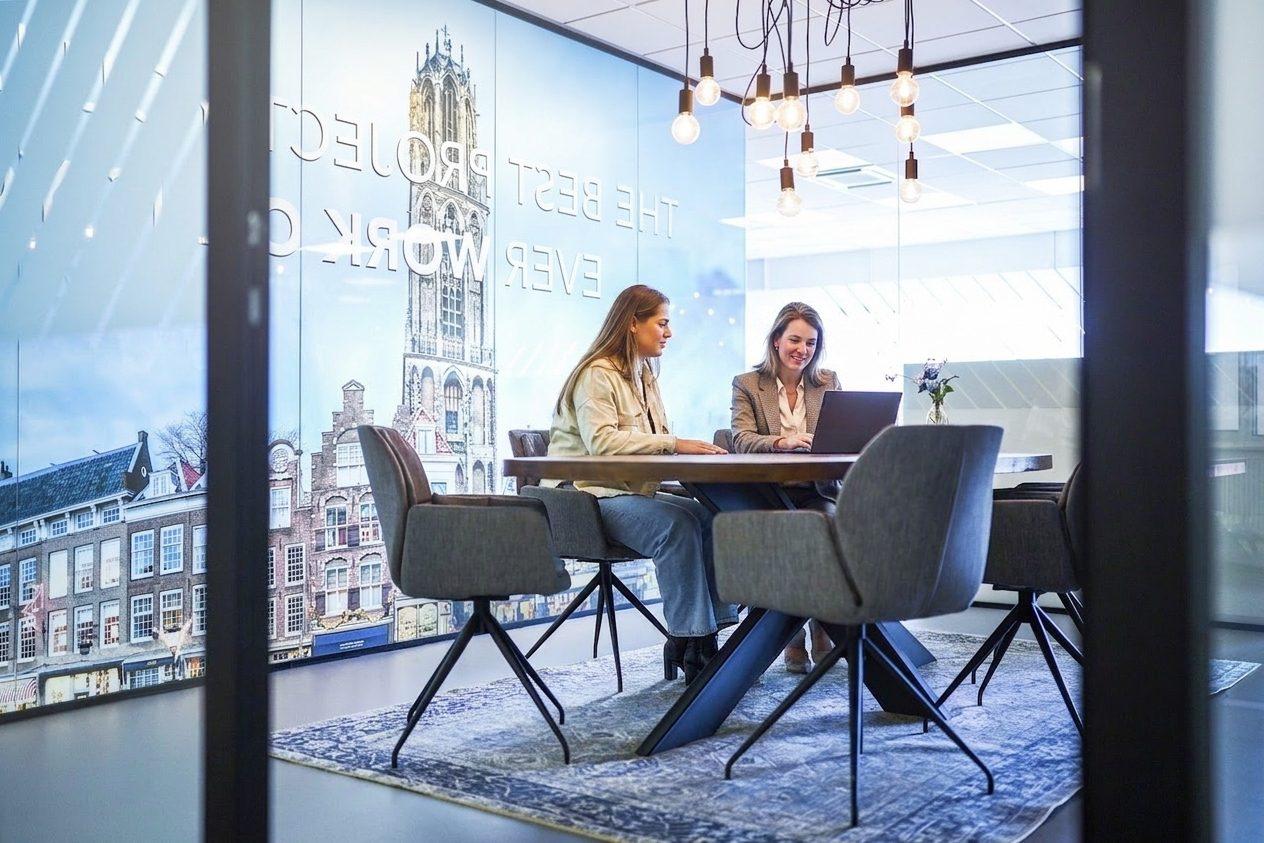 Twee Work-on talentcoaches aan tafel, met de Utrecht Domtoren en 'Work-on' op de muur